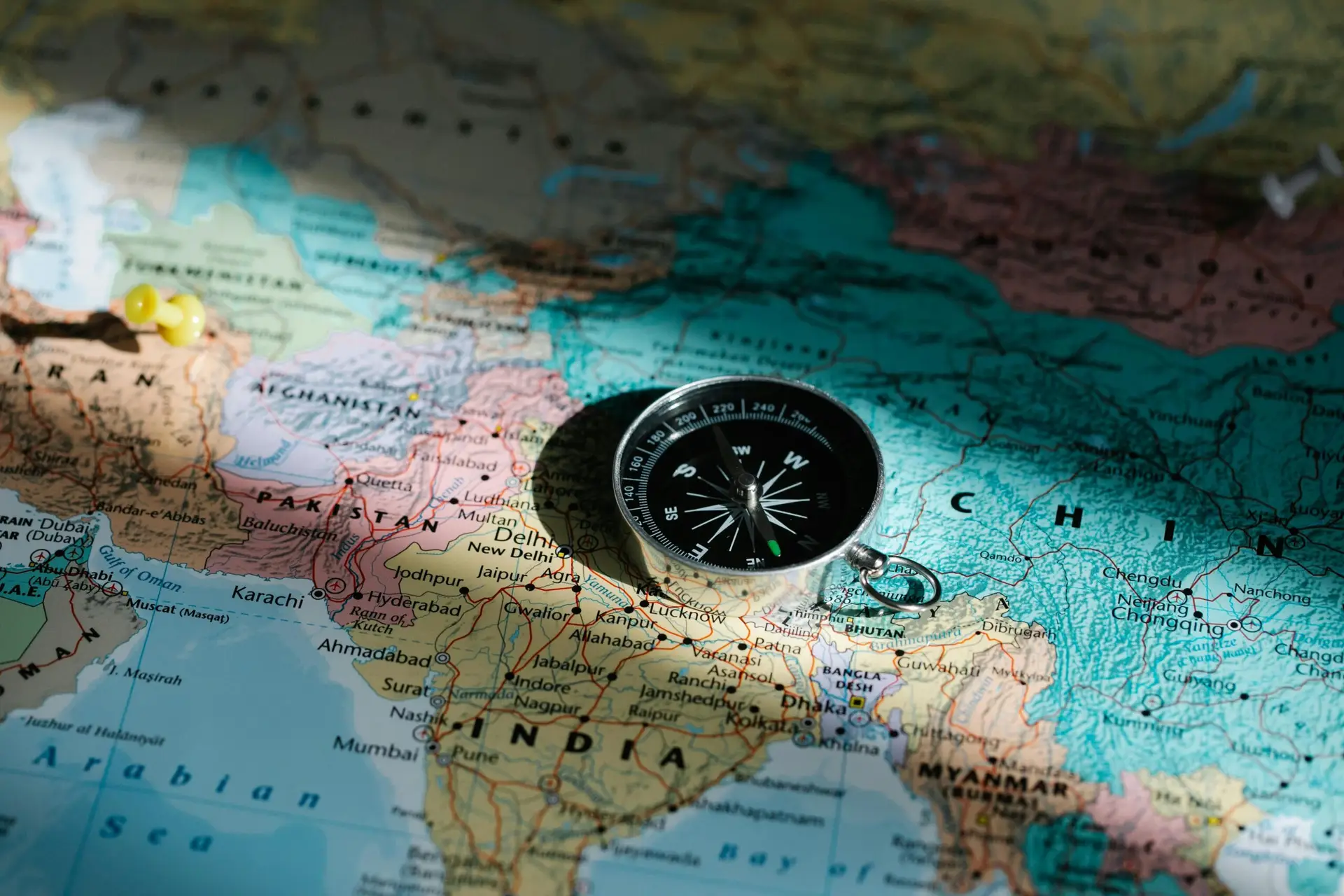 Close-up image of compass on a world map highlighting travel direction and exploration.